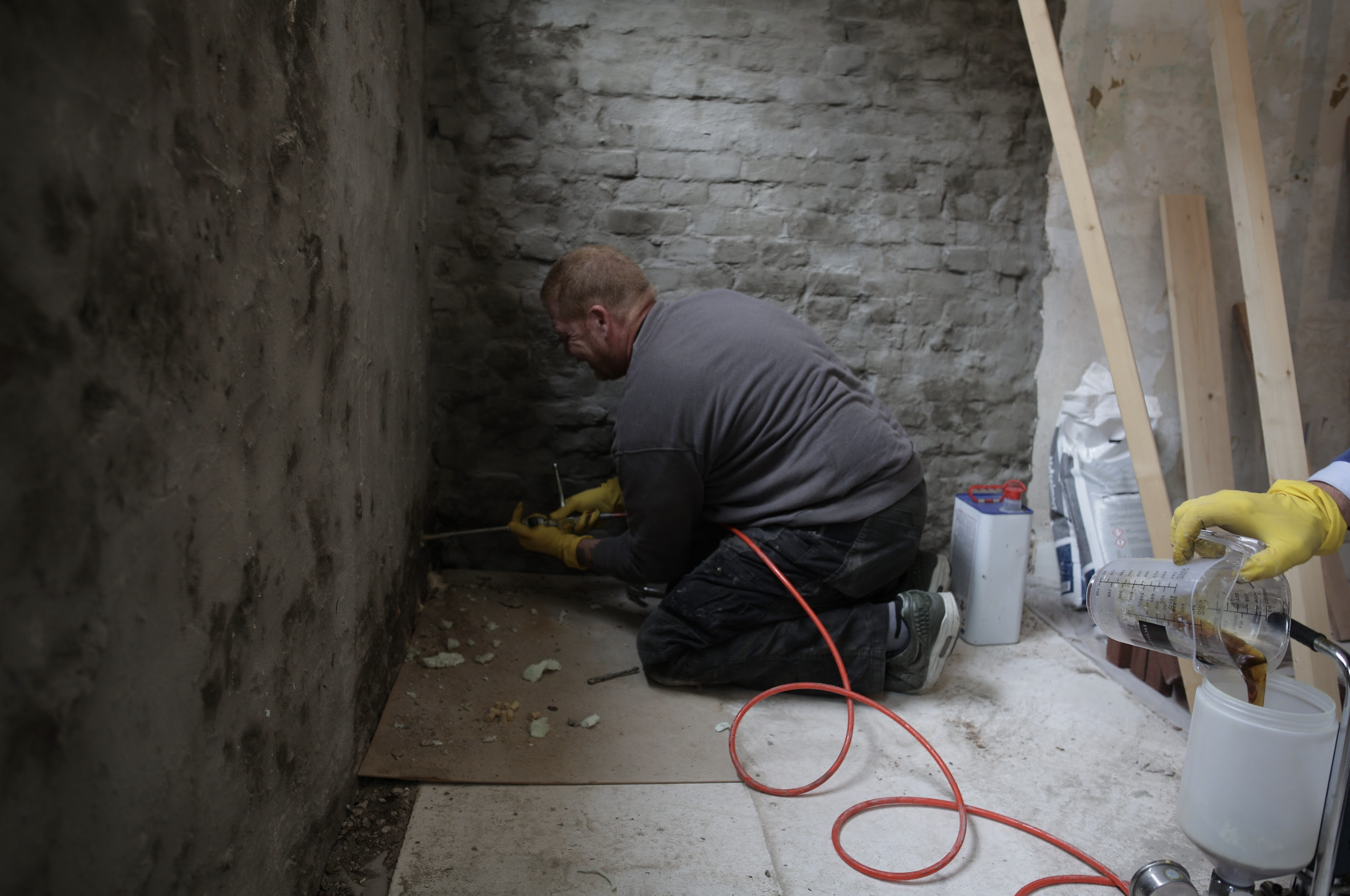 Vochtweg medewerker bezig met het waterdicht maken van een muur