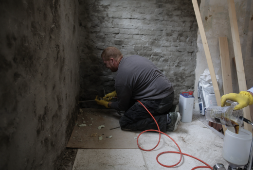 Vochtweg medewerker bezig met het waterdicht maken van een muur